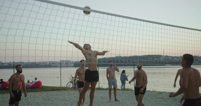 Shirtless men playing volleyball near river