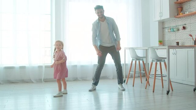 Happy young father and little preschool girl dancing in the living room. Cute princess and her daddy in the room.
