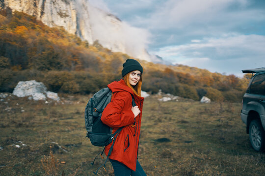 woman model In a red jacket with a backpack in the fall outdoors warm hat fallen leaves