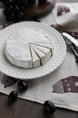 Camembert on a white plain plate. White cheese. Minimalistic photo.