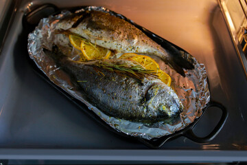 Cooking fish in the oven.Cooking dorado with cherry tomatoes and herbs on parchment in the oven.The supper is ready.We bake sea bass on a grill.Girl cooks fish and takes it out of the stove.World food