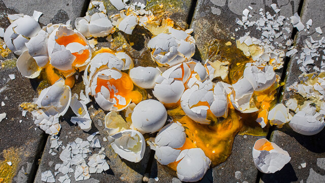 Broken eggs yoke and eggshells making a terrible mess on the ground.