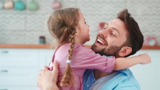 Cute little girl hugging daddy in living room. Young family having fun