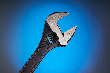 Adjustable wrench with black handle on a blue background