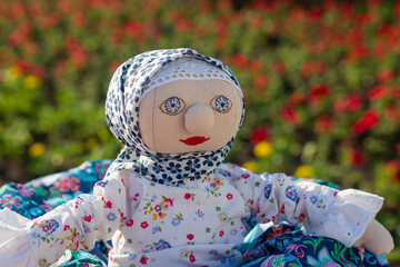 A toy made of fabric against a background of flowers.