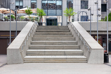 The steps of a granite staircase leading up to the wide entrance of the business center.