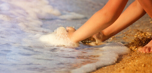 Child plays with sand and collects seashells on the seashore. The concept of summer, relaxation, freedom.