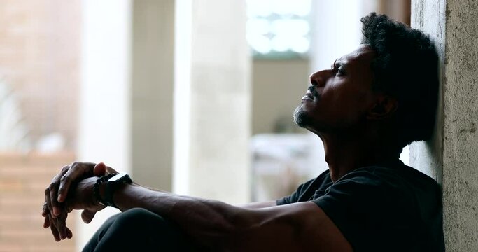 Pensive black man sitting on floor during hard difficult times