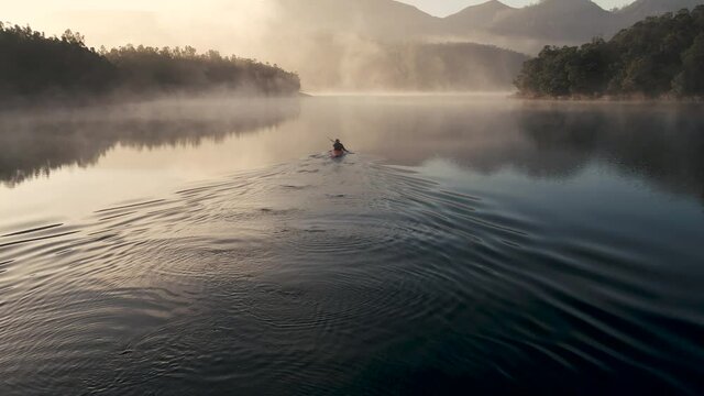 4K Drone footage of young Indian kayaking in a misty lake surrounded with mountains in Kotagiri, Nilgiris, Chennai Tamil Nadu, India 60FPS for slow motion