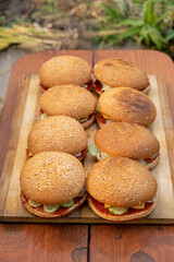 Hamburger holiday menu. Burgers are prepared in outdoors from buns, fried cutlets, vegetables, slice of cheese, tomato, ketchup, sauce