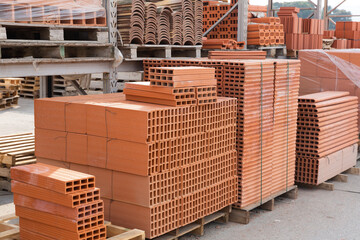 Pallets with stack of redbricks lying at warehouse of building materials in sunny day