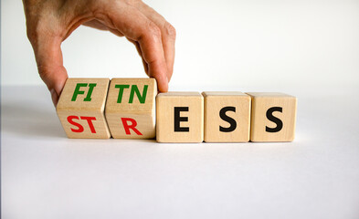 Fitness vs stress symbol. Doctor turns cubes and changes the word 'stress' to 'fitness'. Beautiful white table, white background. Medical, psychological, fitness vs stress concept. Copy space.