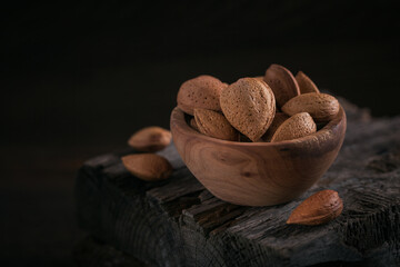 Pile of Almond nuts in a bowl on a dark wooden background