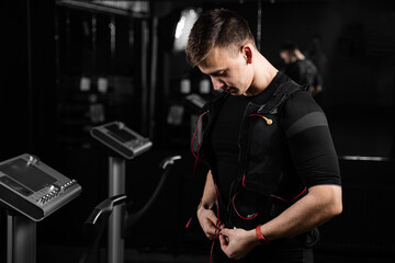 Fototapeta na wymiar Wearing EMS suit in gym. Sport training in electrical muscle stimulation suit.