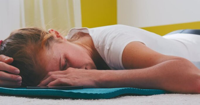 Gym at home. Tired woman lies on the floor at home after workout. Caucasian slim woman relaxes in the bright room