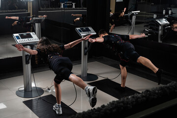 EMS group training for two men and women in the gym. Electrical stimulation for muscles of body.