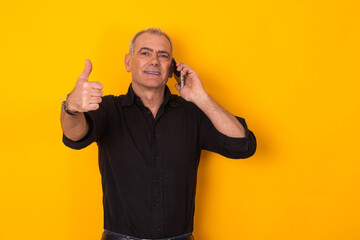 businessman talking on the phone isolated on yellow color background with okay sign