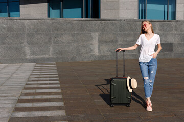 Fototapeta na wymiar attractive girl with a suitcase stands and waits for the bus in summer