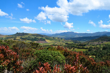 A view of the mountains, green foliage and blue sky at the natural park of Guatavita, located in...