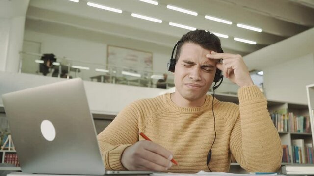 The student guy is tired of studying remotely at the laptop, disappointed from the webinars