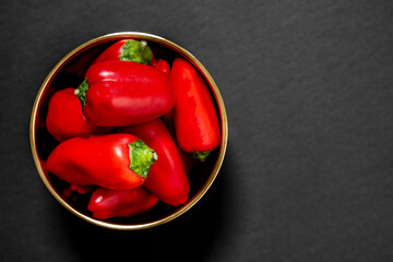 Top view of small red bell peppers inside a golden bowl