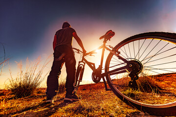 Deportes de bicicleta y concepto de aventurero.. Deportes extremos con bicicleta de montaña y puesta de sol en paisaje natural.Entretenimiento y ocio deportivo saludable - obrazy, fototapety, plakaty