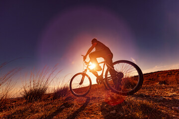 Deportes de bicicleta y concepto de aventurero.. Deportes extremos con bicicleta de montaña y puesta de sol en paisaje natural.Entretenimiento y ocio deportivo saludable - obrazy, fototapety, plakaty
