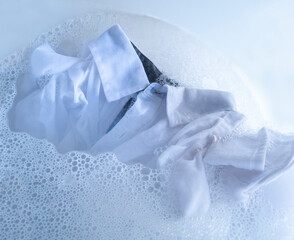 white shirt soaking in water with detergent and foam bubbles