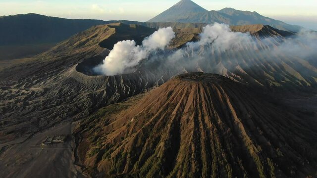 Clouds of smoke on Mount Bromo volcano, Indonesia. Aerial view of mount as active volcano with crater in depth. Brown dirt around.