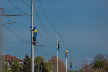 Painters or maintenance workers repairing catenary or electric poles for electricity on a railway or railroad line. Row of workers on poles