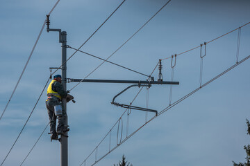 Painters or maintenance workers repairing catenary or electric poles for electricity on a railway or railroad line. Single worker on poles