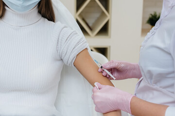 Obraz premium Vaccination of a girl against flu and coronavirus infection during a worldwide pandemic. The formation of the immune system and antibodies.