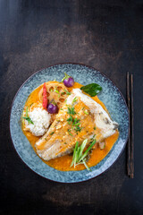 Modern style traditional Thai kang phet with helibut fish filet in curry with vegetable and rice on as top view on a design plate with copy space