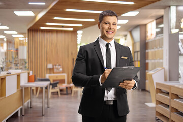 Receptionist in a hotel lobby holding a clipboard - obrazy, fototapety, plakaty