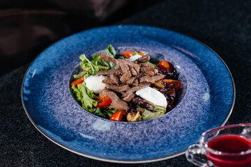 Prepare a delicious fresh salad of tomato greens, cheese, veal and cashew nuts. Delicious healthy food.