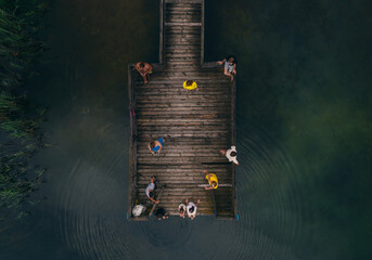 wooden pier on the lake and people resting on it top view