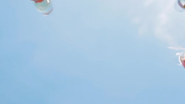 Celebration. Five hands holding the glasses of sparkling wine making a toast, blue sky background.
