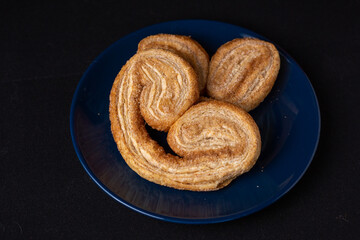Palmier cookie highlighted on dark plate and background