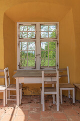 Fenster an orangefarbener Wand mit Holztisch