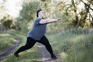 Overweight woman in sportswear training in nature