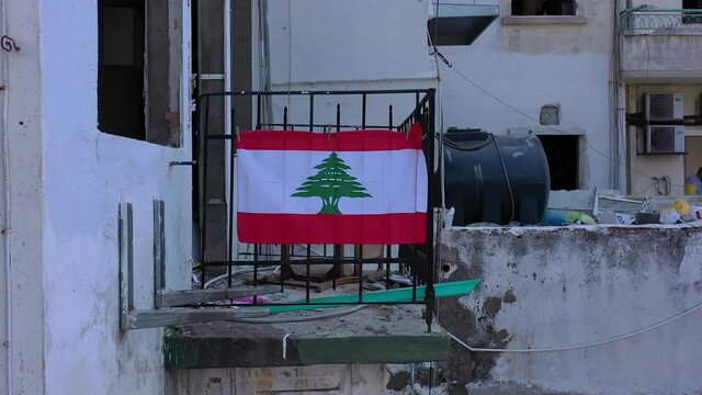 Beirut, Lebanon, 2020: day drone shot reveal going down of the destruction of buildings  due to the 4 August explosion with lebanon flag hanged on the balcony