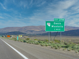 Roadside sign along  Highway 80 with distance and directions to Oasis and Montello in Nevada.