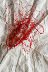red thread on crumpled paper