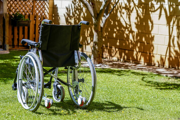 Fototapeta na wymiar Empty wheelchair in the garden, as the hope of a disabled person who has been cured.