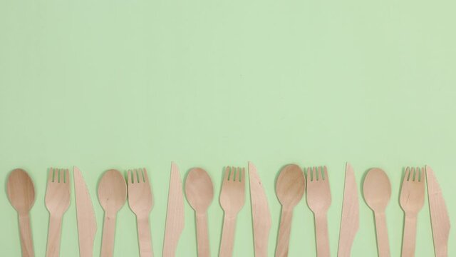 Eco friendly zero waste kitchen utensils cutlery move left right on bottom of light green background. Stop motion