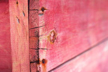 Old red wooden painted planks with rusted nails close up. Summer bright background. Handmade box with cracks.