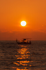Fishing boat at sunset. Evening Mediterranean sea and fishing boat on the horizon. Focus photos on the sun.
