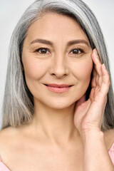 Fototapeta Closeup portrait of gorgeous happy middle aged mature asian woman, senior older 50 year lady looking at camera touching her face isolated on white. Ads of lifting anti wrinkle skin care cream. obraz