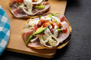 Corn toast with ham and Oaxaca cheese on dark background. Mexican food
