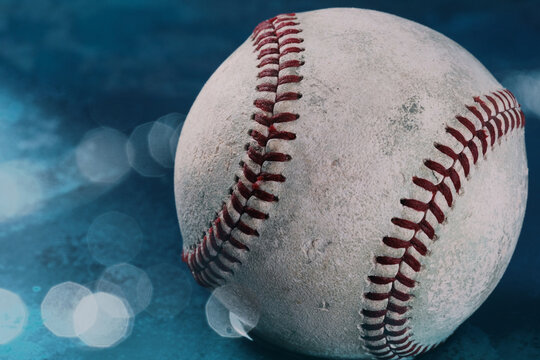 Close up image of baseball used in game against blue background with bokeh and copy space.